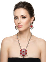 Famaza Couture hand-painted red enamel beaded strand statement necklace with large circular pendant, matching chandelier teardrop dangle earrings, oxidised silver-tone finish, worn on model, elegant South Asian ethnic jewelry.
