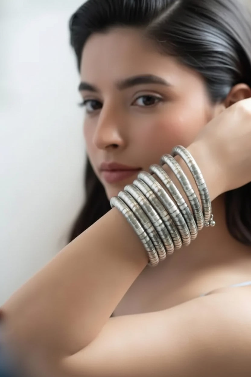A woman wearing a multi-strand slip-on silver-toned segmented spiral cuff bracelet on her arm, posing for a portrait.