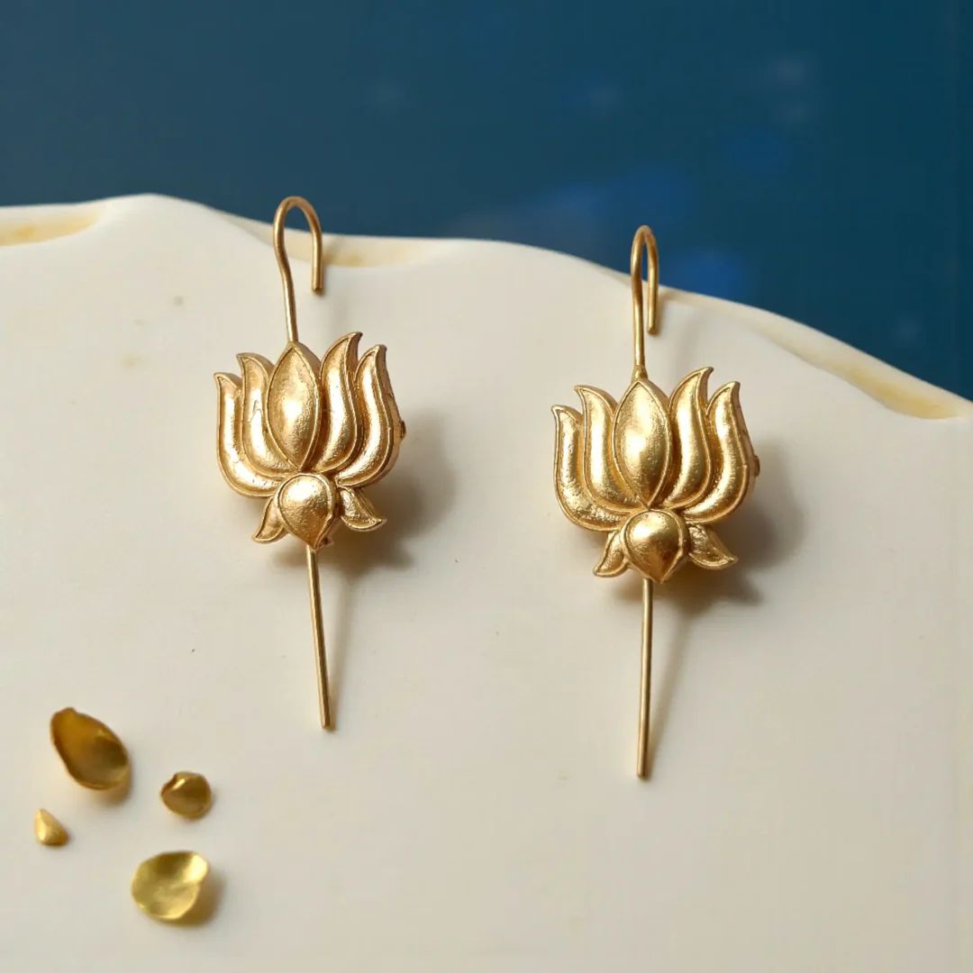 Front view of gold-plated lotus flower ear climbers displayed on a table, highlighting the polished finish and intricate petal details.