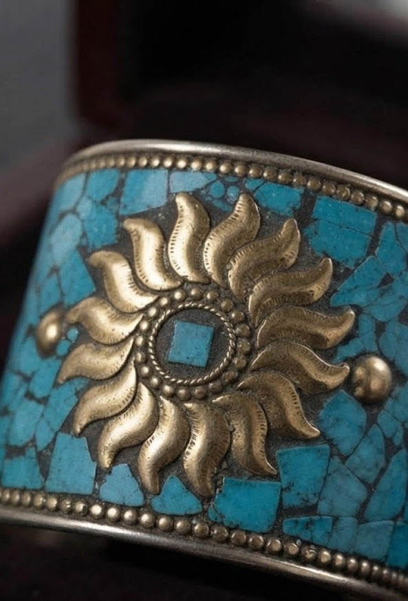 A close-up view of the Persian Royal Heirloom Turquoise Sunflower Cuff, a wide artisan bracelet featuring an intricate turquoise mosaic inlay with a prominent central gold sunflower emblem, showcased by a model in an elegant black velvet setting.
