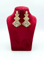 A pair of gold-tone three-tiered chandelier earrings with intricate filigree lattice metalwork and sparkling cubic zirconia crystals, displayed on a red velvet jewelry bust.