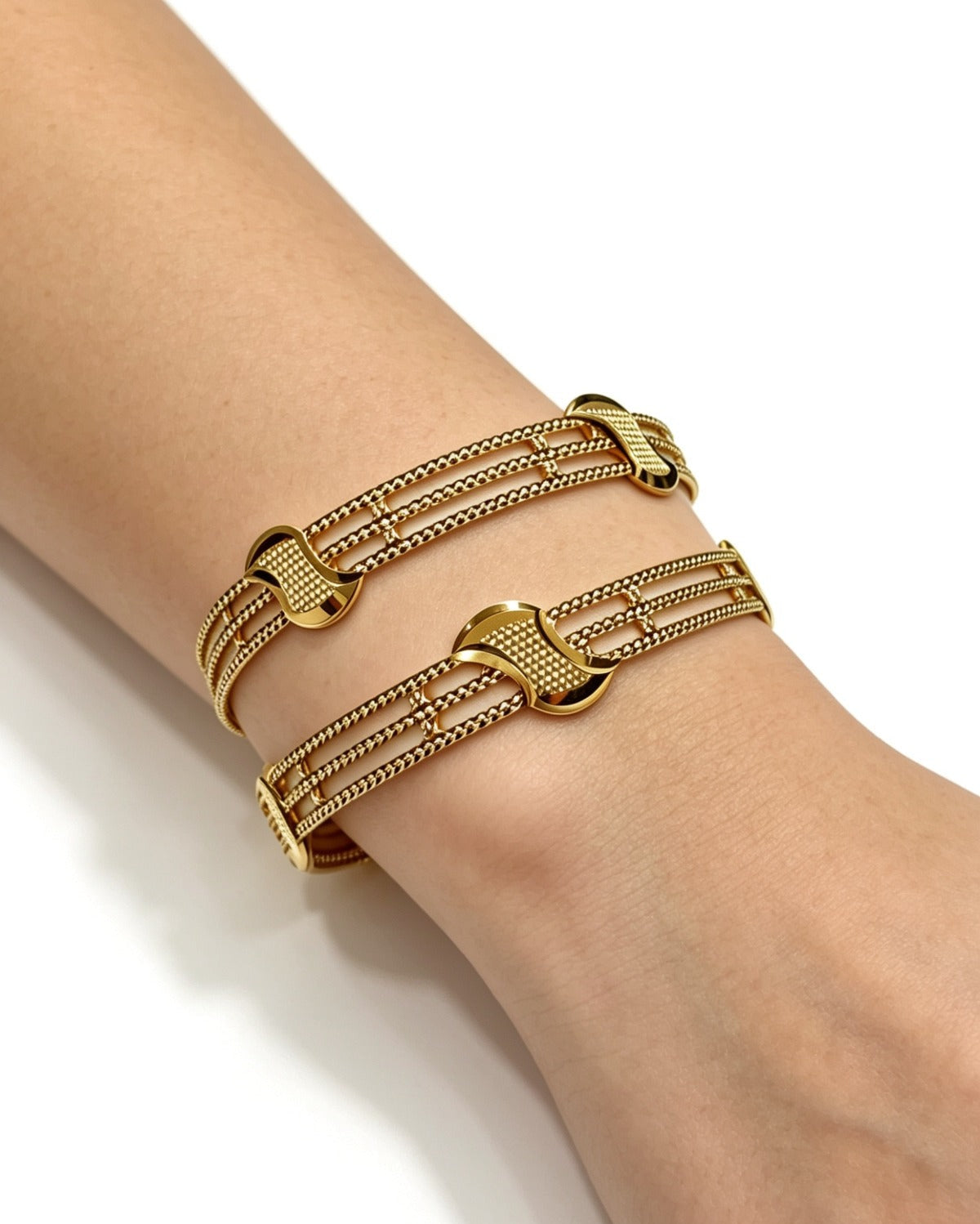 A pair of premium gold-tone interlocking design bangles worn on a wrist, featuring a delicate lattice structure and a high-shine, non-openable solid profile by Famaza Couture.
