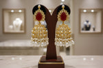 Gold and red earrings on a wooden stand with a blurred jewellery store background