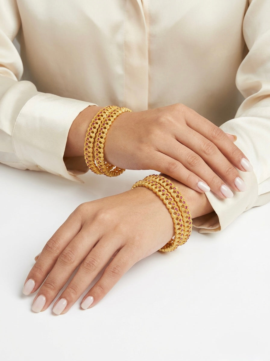 Gold bracelets on a person's wrist against a white background