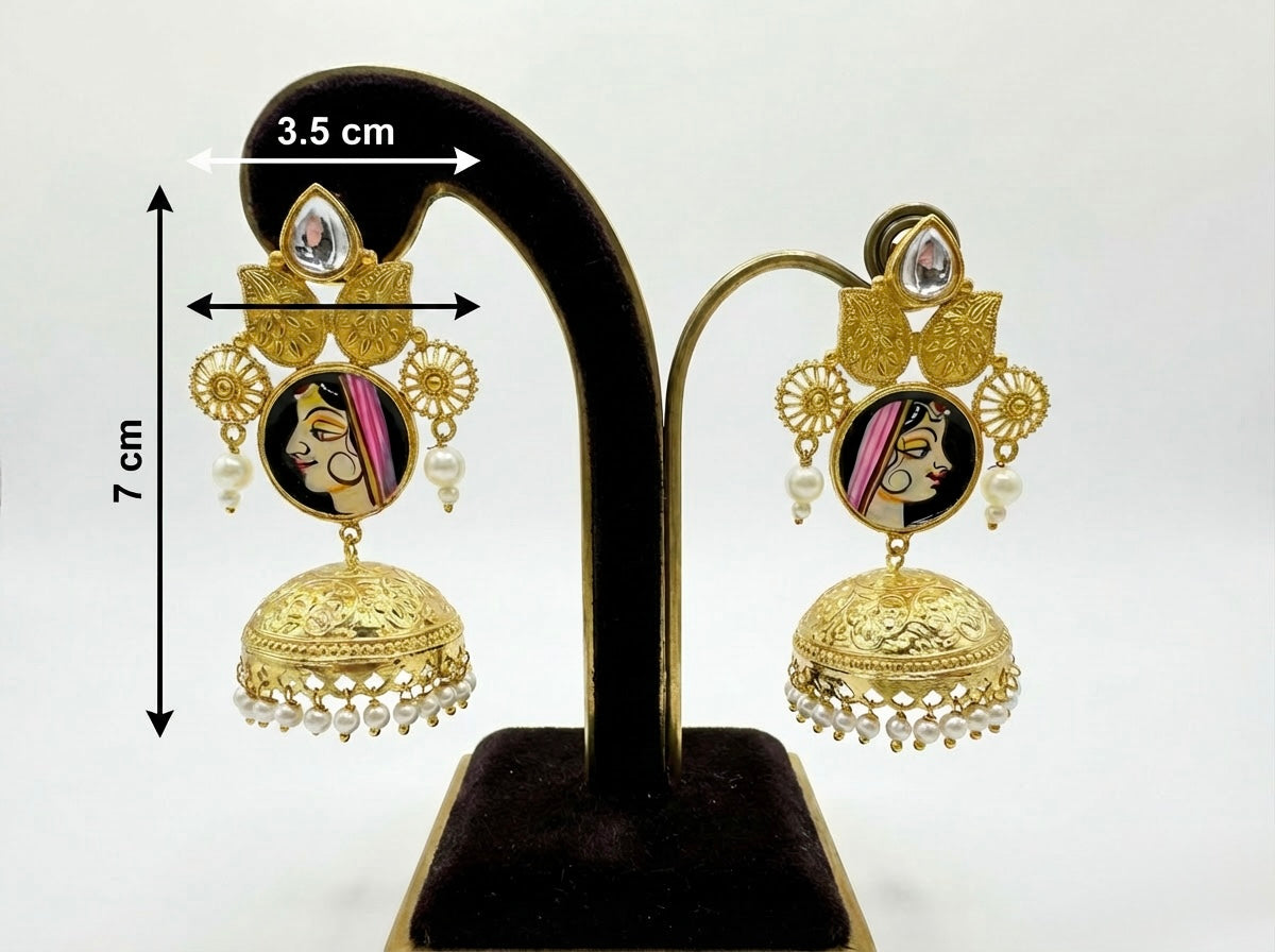 Gold earrings with face design on a black stand with measurements.