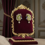 Gold polished peacock figure earrings with vibrant green, blue, and gold enamel accents, along with sparkling white ad stones embellishments. Earrings are focused to show the design.