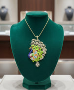 Gold polished a peacock pendant with vibrant green, blue, and gold enamel accents, along with white AD stones sparkling embellishments. Pendant is focused to show the design.