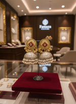 Gold stud with oxidised dome in the bottom and nano pearls double line hanging pearls jhumka earrings and pearl earrings on display in a jewellery store with 'Famaza Couture branding.