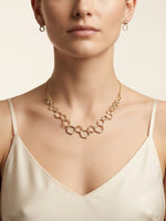 A model wearing a sophisticated 18k gold plated geometric necklace composed of linked hexagons with matching stud earrings, showcasing elite craftsmanship and contemporary elegance.