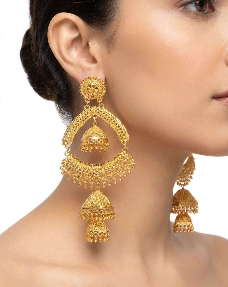 A posh model wearing Grand Heritage gold-plated earrings featuring a luxury filigree arch with a triple-tier jhumka drop.
