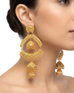 A posh model wearing Grand Heritage gold-plated earrings featuring a luxury filigree arch with a triple-tier jhumka drop.