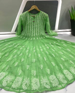 Green embroidered dress on a hanger with a neutral background