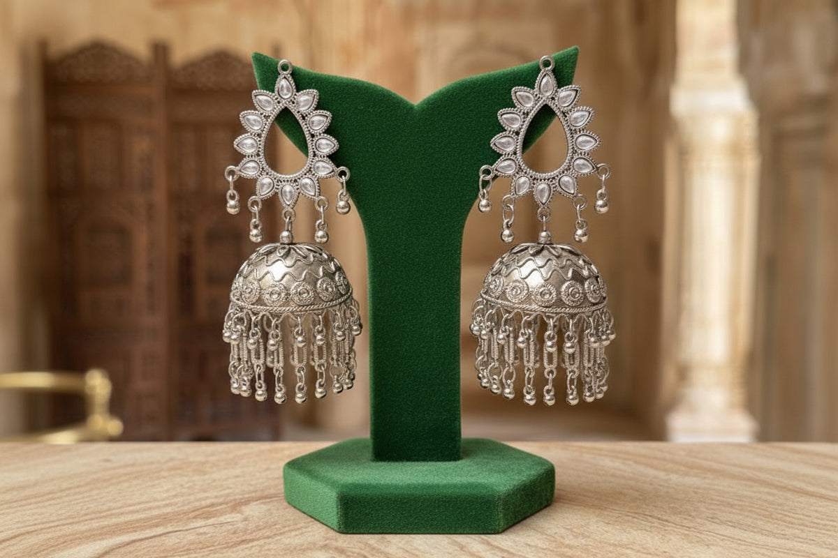 Silver-toned traditional Indian jhumka earrings displayed on a black stand, with overlaid dimension labels showing drop length, top stud width, and bottom dome diameter.
