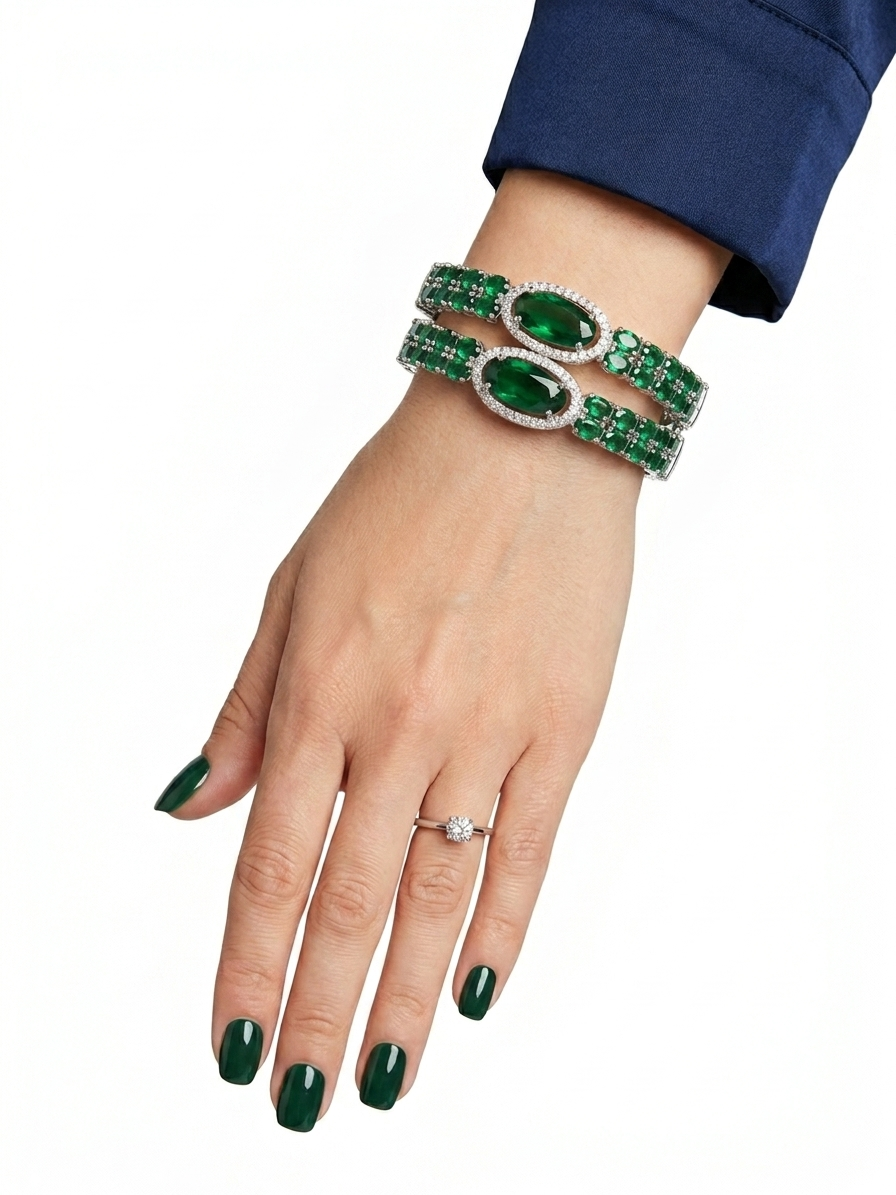 Hand wearing a green emerald bracelet and ring on a white background