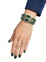 Hand wearing a green emerald bracelet and ring on a white background