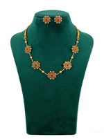 Traditional gold-tone choker necklace and matching stud earrings featuring circular sunburst motifs with red and green nano stones and white pearl accents on a green display stand.