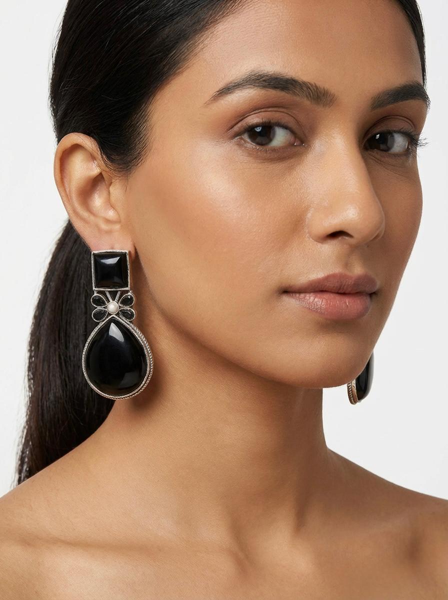 Handcrafted oxidised earrings with a central floral motif and a polished Classic Black Mona Lisa teardrop stone.