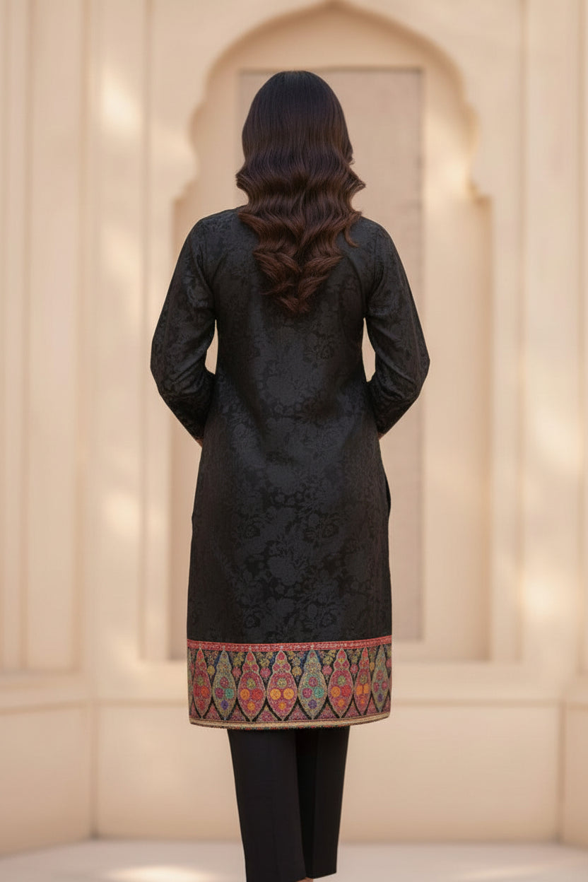 Back view of a woman wearing a black silk kurta set with detailed Kanni embroidery on the hem and a matching embellished dupatta.