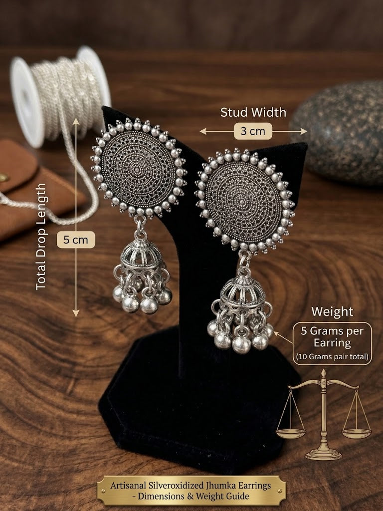 Silver oxidized jhumka earrings displayed on a black stand over a wooden surface, with measurement callouts showing stud width 3 cm and total drop length 5 cm, plus weight text and a small scale graphic.