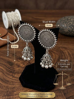 Silver oxidized jhumka earrings displayed on a black stand over a wooden surface, with measurement callouts showing stud width 3 cm and total drop length 5 cm, plus weight text and a small scale graphic.