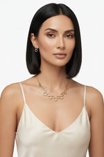 A model wearing an exquisite 18k gold plated geometric necklace featuring a honeycomb-inspired pattern with matching earrings, highlighting elite craftsmanship and unparalleled refinement.