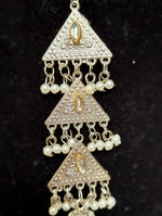 A close-up of a traditional Indian silver-toned jhumka earring with three stacked triangular motifs, adorned with small white pearl beads and gold accents on a black background.
