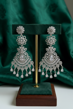 Luxury silver American Diamond chandelier earrings hanging elegantly on a jewelry display stand.