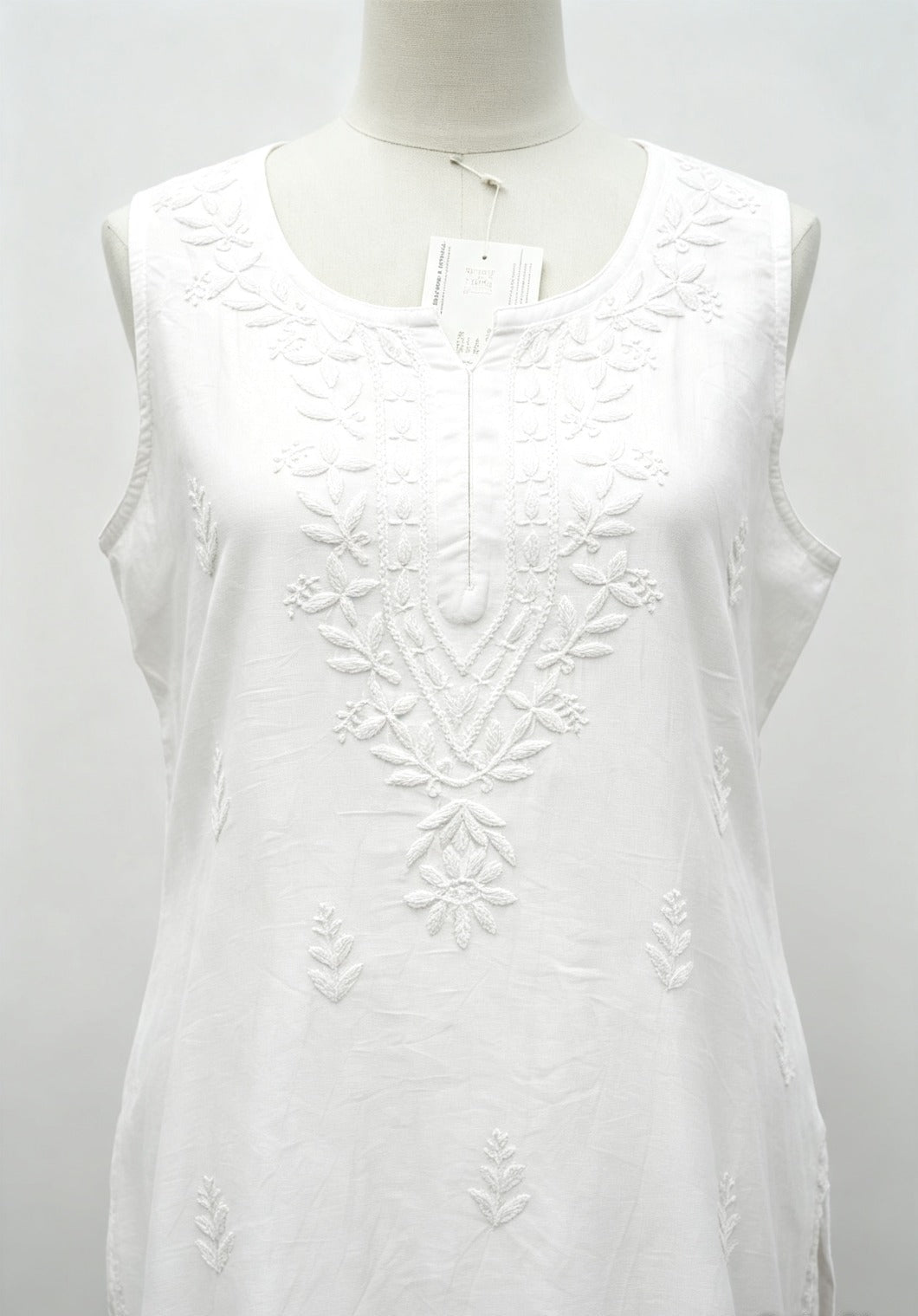 Close-up front view of a white handcrafted sleeveless Chanderi silk Chikankari co-ord set displayed on a mannequin, highlighting the detailed tonal white embroidery along the neckline and front panel.
