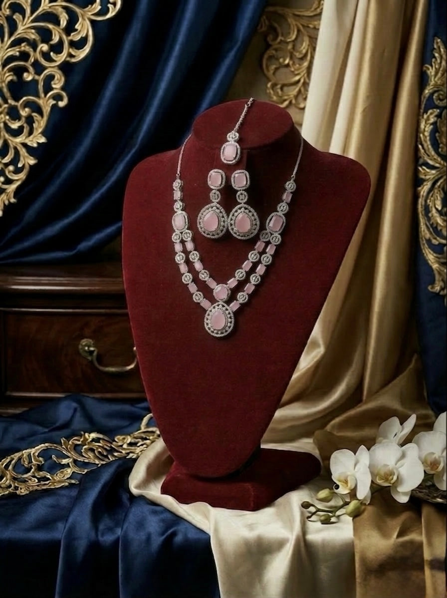 Jewellery set on a red velvet stand with ornate drapes and flowers in the background