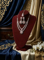 Jewellery set on a red velvet stand with ornate drapes and flowers in the background