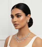 A silver and gold jewellery set displayed on a black velvet mannequin bust, featuring a lace-like collar necklace with leaf-shaped charms and a matching Star shape studs. 