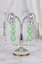 A pair of high-end three-tier drop statement earrings with a shimmering, iridescent lime-green finish displayed on a rose gold ear-shaped jewelry stand. Infographic text indicators specify a drop length of 8cm and a single earring weight of 8g.