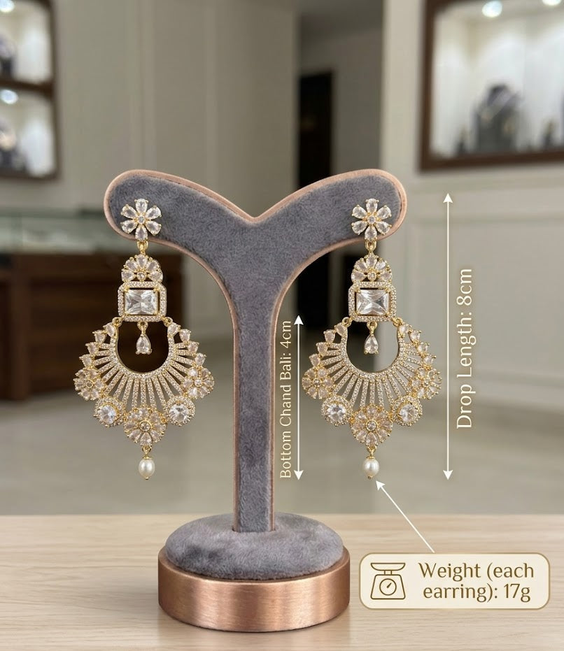 A studio product shot of gold-toned chand bali earrings displayed on a grey velvet jewelry stand, annotated with technical specifications: total drop length of 8cm, bottom chand bali section of 4cm, and a weight of 17 grams per earring.