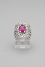 Luxurious silver-tone cocktail ring featuring a round vibrant ruby pink centre stone surrounded by marquise and round-cut cubic zirconia accents in an intricate halo setting, with a textured honeycomb-patterned band, displayed on champagne and emerald green satin, premium American Diamond jewellery.
