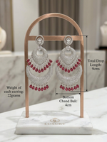 Luxury American Diamond and ruby gemstone chaand bali statement earrings in a silver finish. Features tiered crescent layers with dangling teardrop red stones, perfect for bridal and festive wear