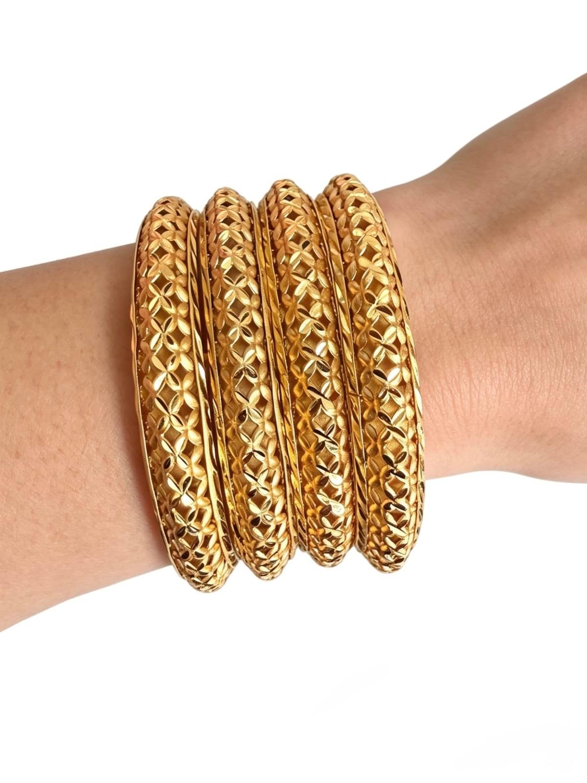 A set of four micro-gold plated copper bangles featuring an intricate fan-pattern lattice cutwork design, shown worn on a wrist to highlight the detailed craftsmanship.