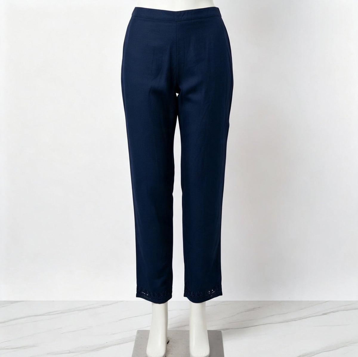 Mannequin display focusing on the matching navy blue trousers of the co-ord set, featuring detailed trim embroidery at the hems against a white marble floor.