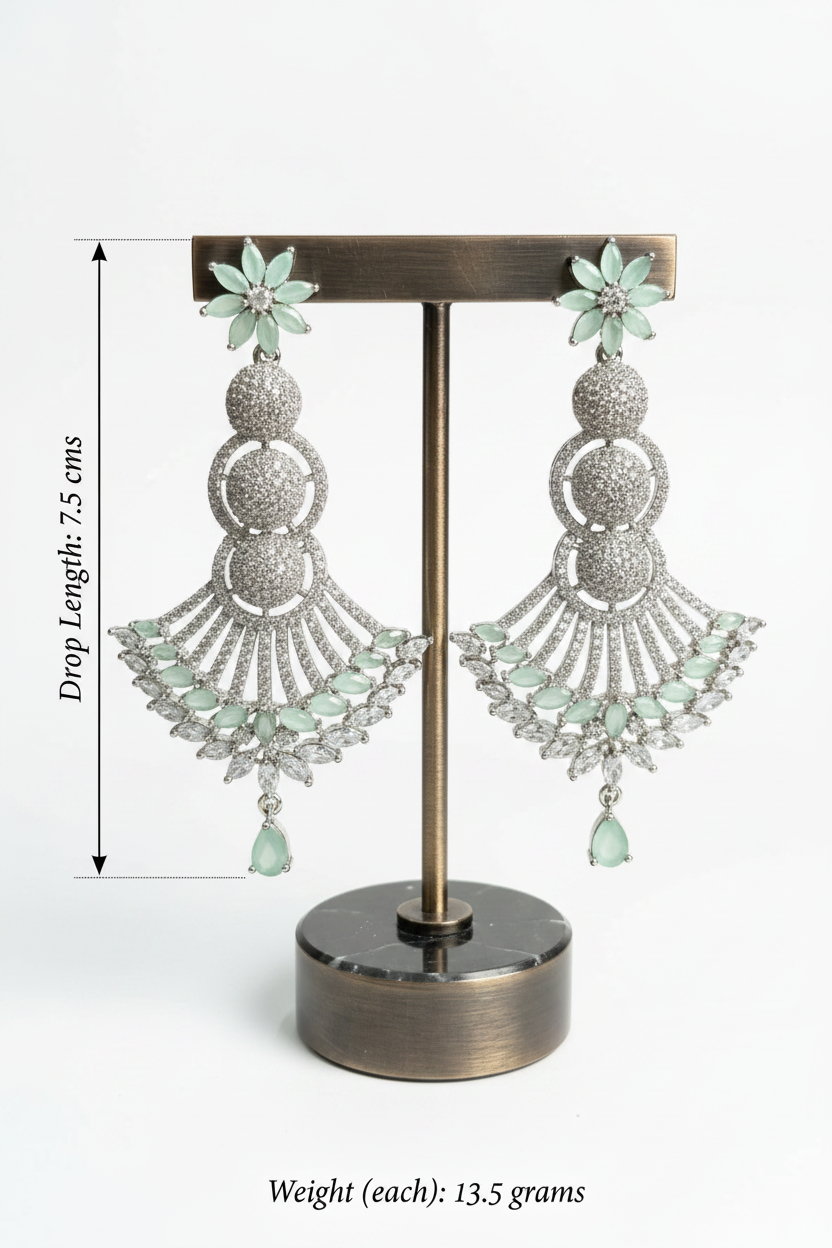 Pair of silver earrings with green accents on a stand, showing dimensions and weight.