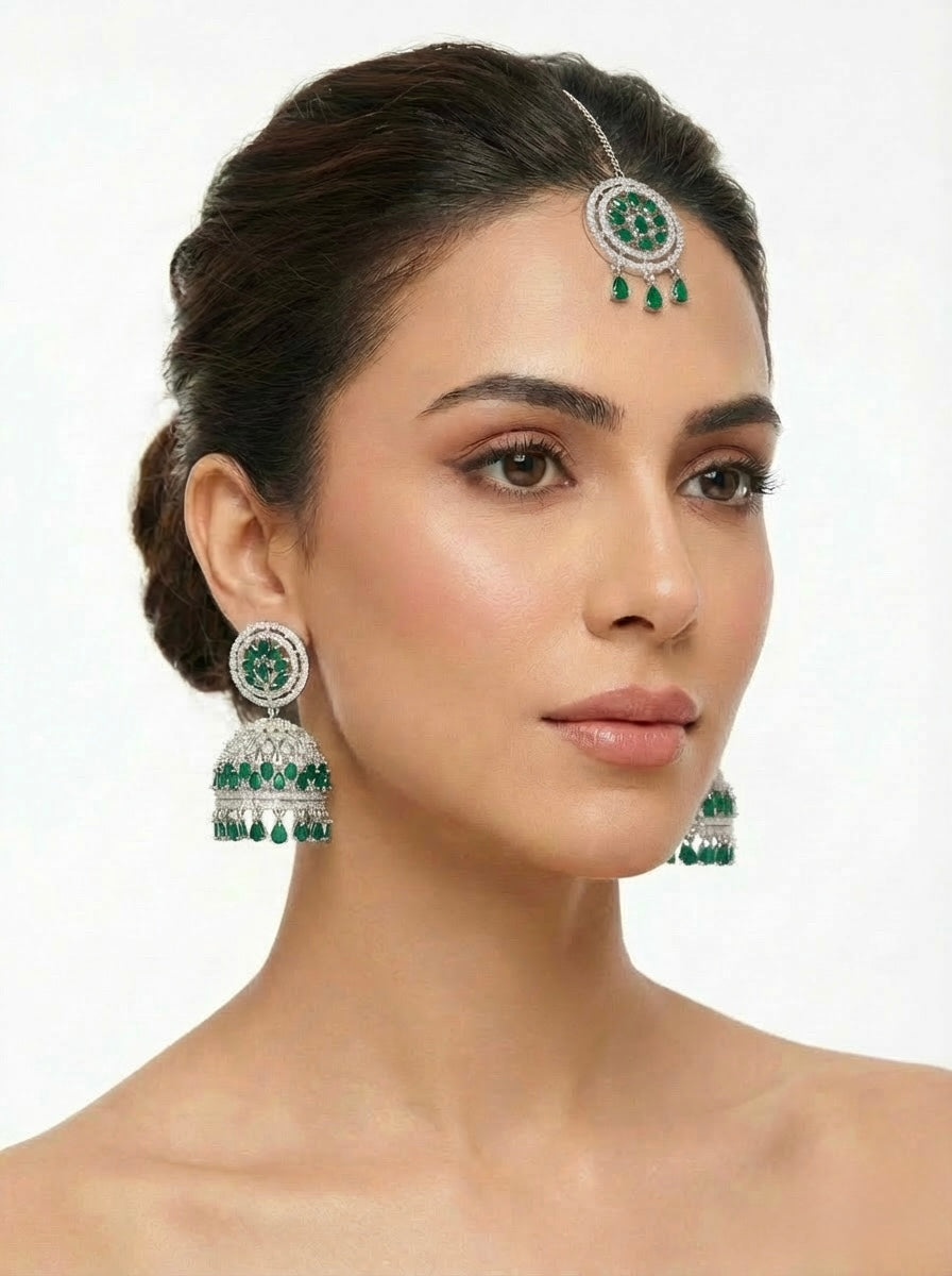 Model is wearing imitation AD stones earrings and maang tikka with bottle green and white stones