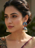 Model wearing statement 5.5cm blue and red peacock jhumkas with traditional Meenakari enamel artistry.