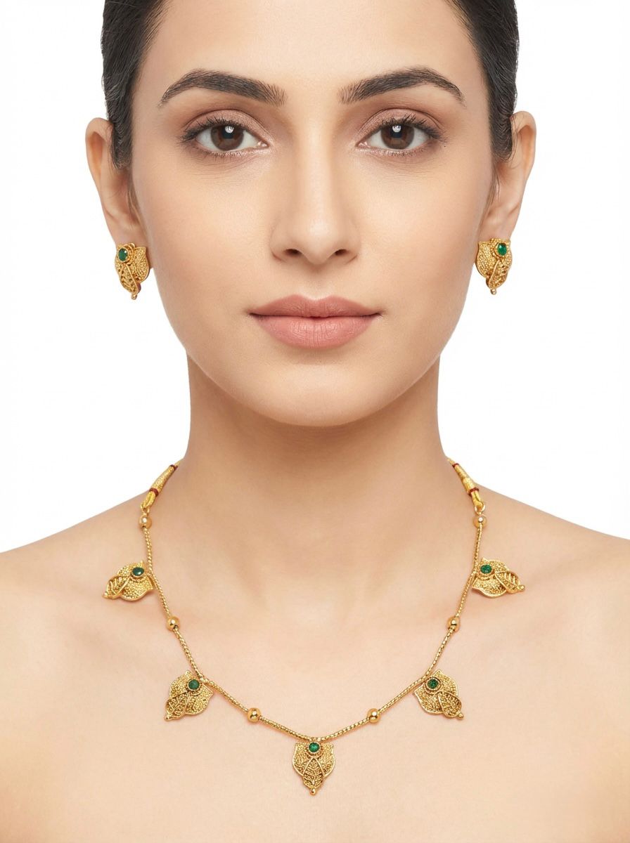 Model wearing the royal gold-toned brass necklace with a faceted bottle green teardrop stone and matching studs.