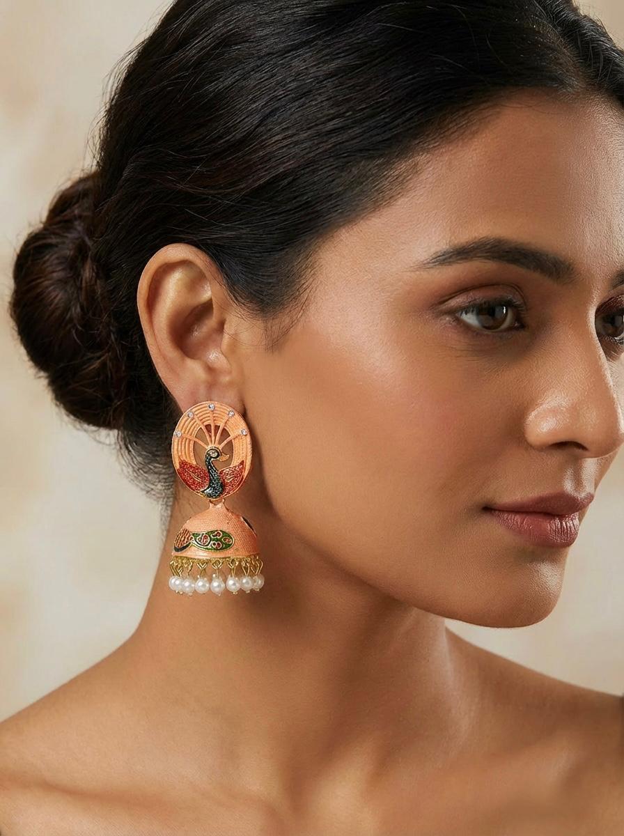 Model wearing vibrant 5.5cm orange peacock jhumka earrings featuring traditional Meenakari artistry.