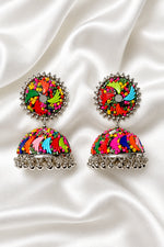 Vibrant multicolor hand‑painted fan design mirror & seed bead silver jhumka earrings on soft white silk background — ethnic bridal festive jewelry.