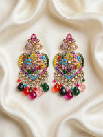 Gold-tone multicolor mosaic heart chandelier earrings with rainbow stones and teardrop bead drops, laid flat on soft cream silk — South Asian bridal and festive jewelry.