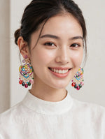 Model wearing gold-tone multicolor mosaic heart chandelier earrings with vibrant pink, red, green, blue, yellow stones and teardrop bead drops — South Asian festive party jewelry.