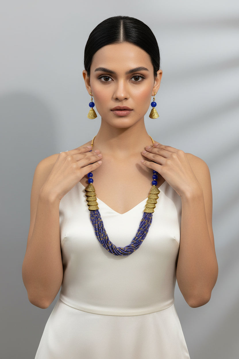 Necklace and earrings set with blue beads and gold accents on a black stand.