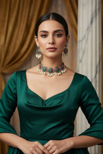 Necklace and earrings with green and hot pink accents on a clear plastic sheet.