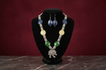 Necklace with blue, green, and yellow beads on a black stand