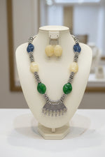Necklace with green and blue stones on a black stand