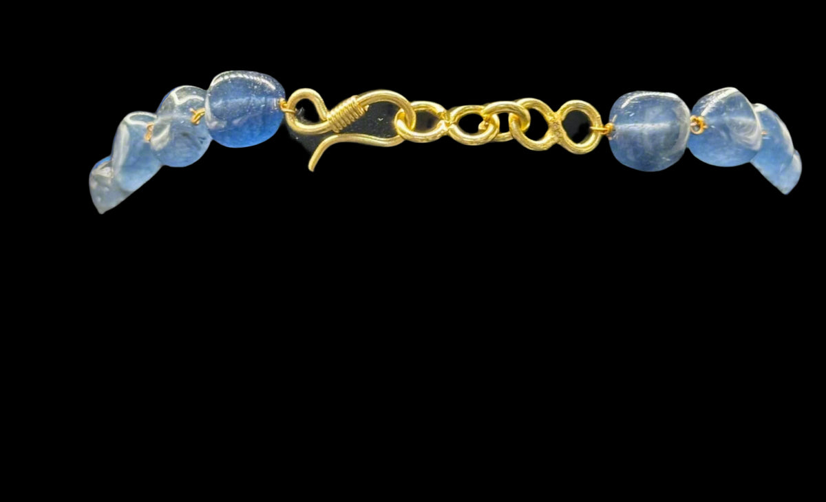 Necklace with navy blue mona lisa stone and golden chain with closing hook on a black mannequin bust against a grey background